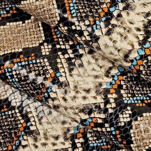 Pode incluir: Close-up de um tecido de pele de cobra com um padr&atilde;o preto, marrom, laranja e azul.