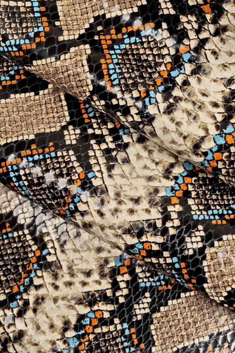 Pode incluir: Close-up de um tecido de pele de cobra com um padr&atilde;o preto, marrom, laranja e azul.
