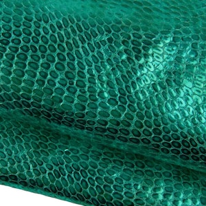 Könnte beinhalten: Ein leuchtend smaragdgrünes Material mit einem erhabenen, sich wiederholenden Schuppenmuster, das die Textur von Schlangenhaut nachahmt. Die Oberfläche hat ein glänzendes, reflektierendes Finish mit tiefgrünen Schatten zwischen den Schuppen.