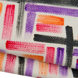 Könnte beinhalten: Nahaufnahme einer strukturierten weißen Oberfläche mit einem farbenfrohen abstrakten Design. Das Design zeigt rechteckige und pinselstrichartige Formen in Rot-, Orange-, Lila- und Schwarztönen. Das Muster erinnert an ein Aquarellgemälde.