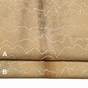 May include: Two pieces of tan cowhide with white stitching in a wavy pattern. The top piece is labeled "A" and the bottom piece is labeled "B".