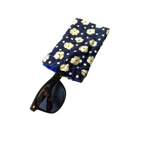 May include: A blue and white floral patterned fabric eyeglass case with a pair of black sunglasses inside.