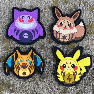 May include: Four rubberized patches featuring stylized character designs. The top left is a purple Gengar, the top right is a brown Eevee, the bottom left is an orange Charizard, and the bottom right is a yellow Pikachu, all with black borders.