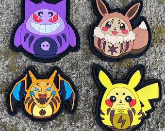 以下が含まれることがあります： デフォルメされたキャラクターデザインのラバー製ワッペン4枚。左上は紫色のゲンガー、右上は茶色のイーブイ、左下はオレンジ色のリザードン、右下は黄色のピカチュウで、すべて黒い縁取りが施されています。