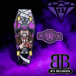 May include: A purple and black skateboard patch in the shape of a coffin, featuring a wrestler graphic. Also, a purple diamond with the number 13, and a wrestling belt patch. The B's Boards logo is at the bottom.