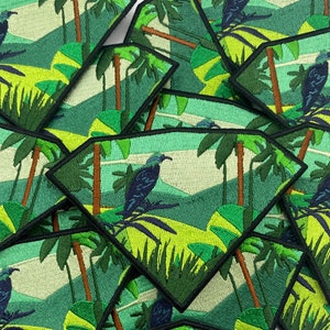 May include: A set of embroidered patches featuring a tropical scene with palm trees and a bird. The patches are green, brown, and yellow.