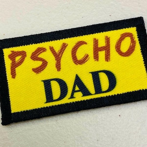 May include: Yellow fabric patch with black stitching and the text "PSYCHO DAD" in brown and black lettering.