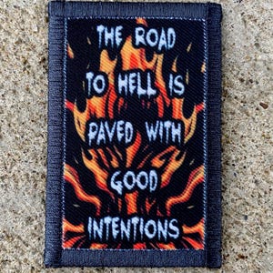 Può includere: Toppa rettangolare con la scritta "THE ROAD TO HELL IS PAVED WITH GOOD INTENTIONS" in bianco, su un disegno di fiamme arancioni e gialle su sfondo nero. Bordo blu scuro.