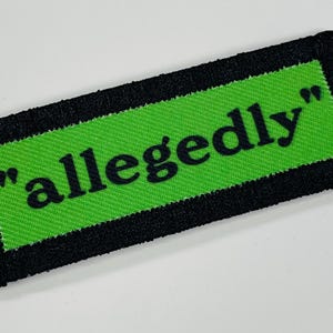 May include: A green patch with black stitching and the text "allegedly" in black.