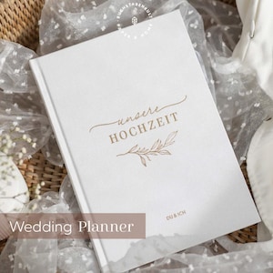 Könnte beinhalten: Ein weißer Hochzeitsplaner mit goldener Beschriftung, die "Wedding Planner" und "unsere HOCHZEIT" mit einem kleinen goldenen Blattdesign sagt. Der Text "DU & ICH" befindet sich in der rechten unteren Ecke.