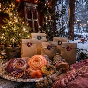 May include: A collection of brown paper bags labeled with numbers 3, 7, 12, 18, and 24, arranged alongside a silver platter filled with various colorful yarn skeins in shades of pink, orange, purple, and gold, plus a wooden spool of yarn.