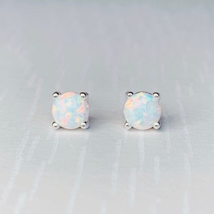 May include: A pair of silver stud earrings with white opal gemstones.