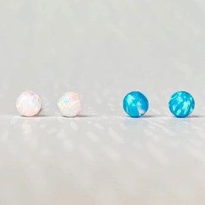 May include: Four small round opal earrings, two white and two blue.