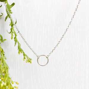 May include: A silver chain necklace with a simple circle pendant.