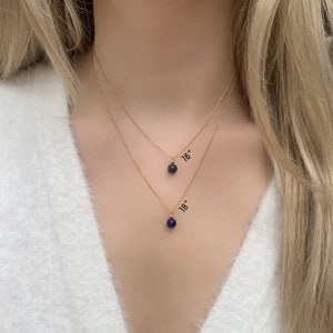 May include: Two gold necklaces with blue gemstone pendants. The top necklace is 16 inches long and the bottom necklace is 18 inches long.