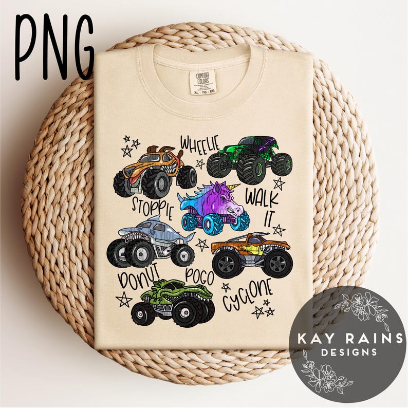May include: A beige t-shirt with colourful monster truck illustrations, including a shark and unicorn design, and phrases such as "Wheelie" and "Walk It." The shirt has a crew neck and short sleeves. The design is aimed at children.