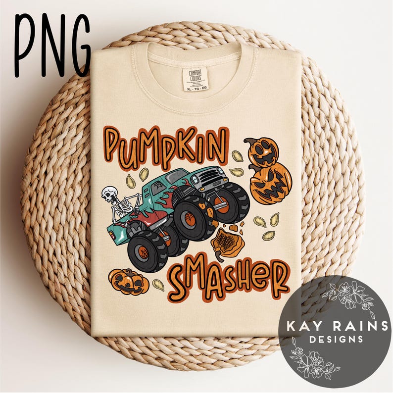 May include: Beige t-shirt with a graphic of a monster truck crushing pumpkins. The text reads "Pumpkin Smasher" in orange and brown. A skeleton is driving the truck. The shirt is on a woven surface.