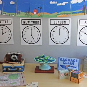 May include: A table setting for a travel-themed party with clocks showing different time zones for Seattle, New York, London, and Paris. There are also suitcases, a globe, and cookies shaped like the Earth.