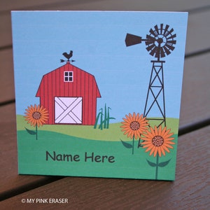 May include: A red barn with a white door and a rooster weather vane on top. There is a windmill to the right of the barn and a green field with orange sunflowers in front of the barn. The text "Name Here" is printed on the green field.