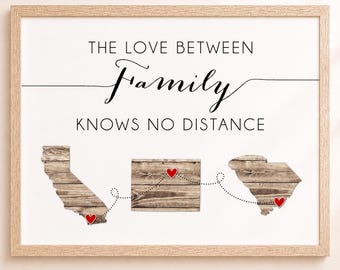 May include: A framed wall art print featuring the text THE LOVE BETWEEN Family KNOWS NO DISTANCE. Below the text are three wooden-textured state map silhouettes connected by a dotted line with small red hearts marking specific locations.