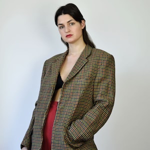 Könnte beinhalten: Ein brauner, schwarzer und grüner karierter Blazer mit einem einzigen Knopfverschluss. Der Blazer hat eine Tasche auf der linken Seite.