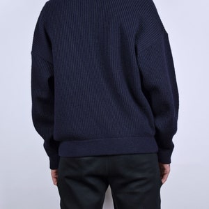 May include: A dark blue ribbed knit cardigan with a long sleeve and a button closure.