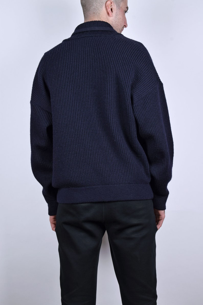 May include: A dark blue ribbed knit cardigan with a long sleeve and a button closure.