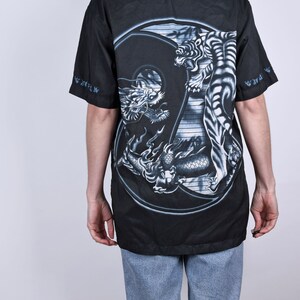 May include: Black button-up shirt with a large yin-yang design featuring a dragon and a tiger in gray and white on the back.
