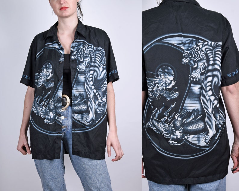 May include: Black button-up shirt with a white tiger and dragon design. The design is a yin-yang symbol with the tiger on one side and the dragon on the other.