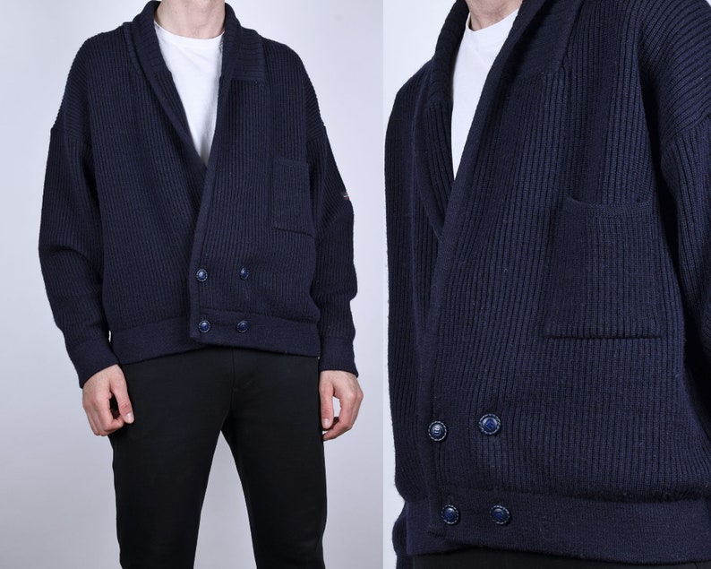 May include: A dark blue knitted cardigan with a shawl collar, two pockets, and a double-breasted button closure.