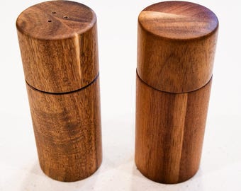 Può includere: Due saliere e pepiere in legno con finitura in legno naturale. Le saliere sono cilindriche e hanno un design semplice.