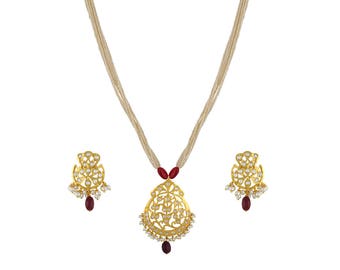 May include: A gold-toned necklace and earring set. The necklace features a pendant with an ornate design, red accents, and a dangling red stone. The earrings mirror the pendant's design. The necklace has multiple strands of off-white beads.