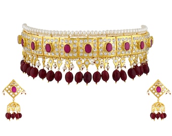 May include: A gold-toned choker necklace and matching earrings set. The necklace features a row of pearls, a gold band with red oval stones, and dangling red beads. The earrings have a similar design with red stones and dangling beads.