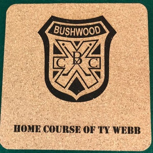 May include: A cork coaster with a black and white logo that says "Bushwood C&C" and "Home Course of Ty Webb".