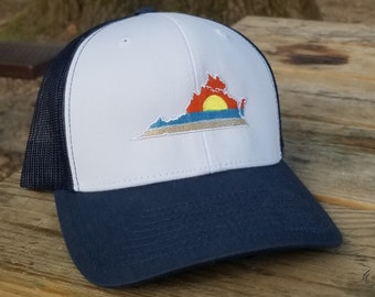 May include: A white and navy blue trucker hat with a white embroidered outline of the state of Virginia with a sunset over the horizon.