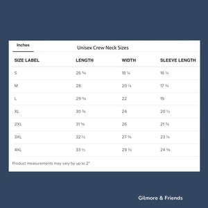 May include: A white chart on a navy blue background displays unisex crew neck sizes in inches. The chart includes size labels S to 4XL, with corresponding length, width, and sleeve length measurements. The text "Gilmore & Friends" is at the bottom.