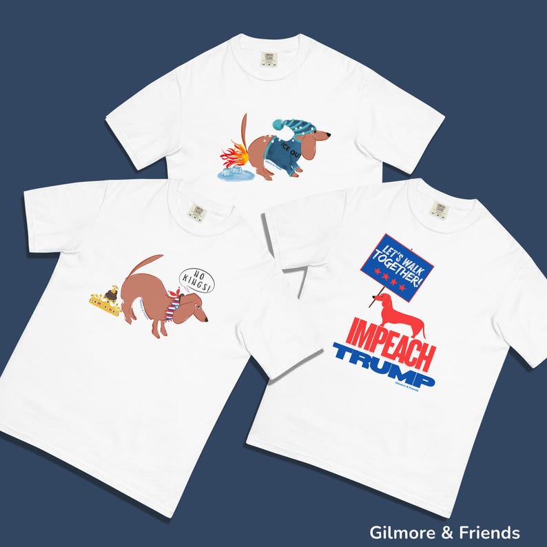 May include: Three white t-shirts with dachshund graphics. One shirt features a dachshund with a sign that says "IMPEACH TRUMP". Another has a dachshund with the text "NO KINGS!". The third shirt shows a dachshund in winter attire.