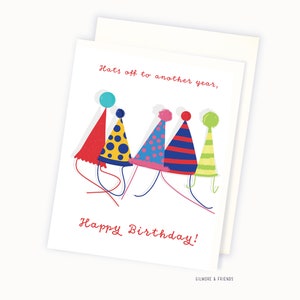 May include: A birthday card with a colorful illustration of five party hats lined up. The card reads "Hats off to another year, Happy Birthday!" and is signed "Gilmore & Friends".
