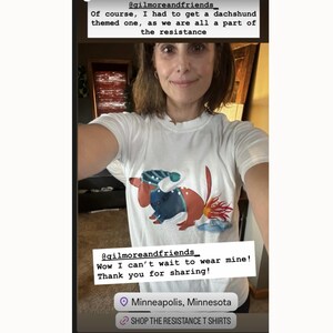 May include: White t-shirt featuring a dachshund design with blue and red accents. The text on the shirt reads "VO 137". The image also includes the text "@gilmoreandfriends" and "SHOP THE RESISTANCE T SHIRTS".