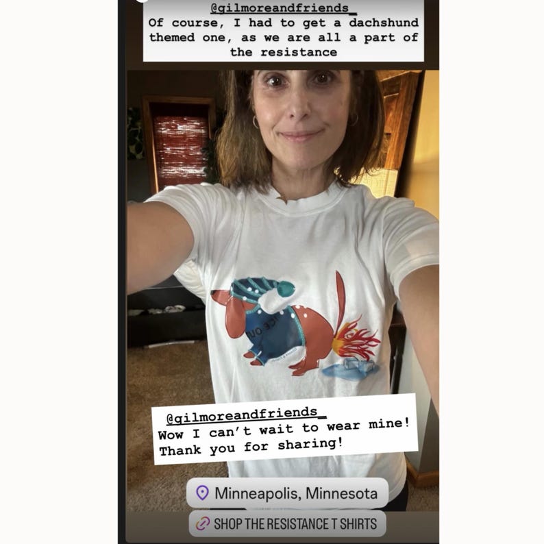May include: White t-shirt featuring a dachshund design with blue and red accents. The text on the shirt reads "VO 137". The image also includes the text "@gilmoreandfriends" and "SHOP THE RESISTANCE T SHIRTS".