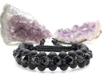 May include: Black beaded bracelet with black crystal accents. The bracelet is made with black cord and features a knot design.