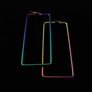 May include: A pair of rainbow-colored rectangular hoop earrings. The earrings are made of metal and have a shiny finish.