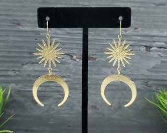 May include: Gold tone earrings with a crescent moon and starburst design.