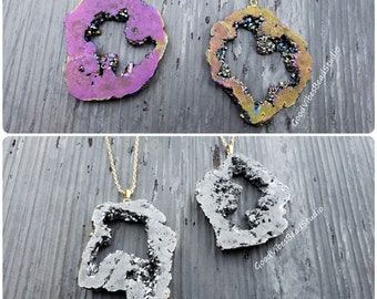 Peut inclure: Quatre pendentifs en cristal d'agate avec des chaînes dorées. Les pendentifs sont de différentes couleurs, notamment le violet, l'or et le gris. Les pendentifs sont tous en forme de cœur avec un trou au centre. Le texte "GoodVibesBeadStudio" est visible dans le coin inférieur droit de l'image.