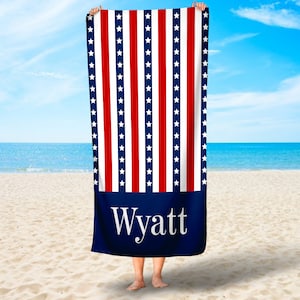 May include: A blue beach towel with red and white stripes and white stars. The bottom of the towel has a blue section with the name "Wyatt" in white text.