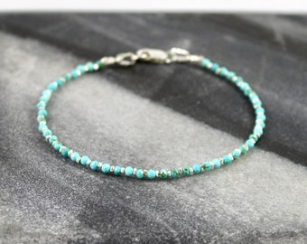 May include: A delicate bracelet featuring small, faceted turquoise beads alternating with tiny, cylindrical silver-toned metal spacers. The piece is finished with a polished silver-toned lobster claw clasp, creating a simple and refined circular design.