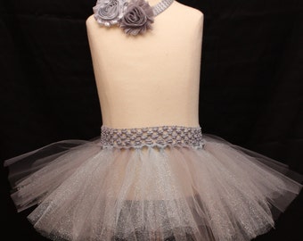 May include: A silver tulle tutu skirt with a silver crochet waistband and a silver flower headband.