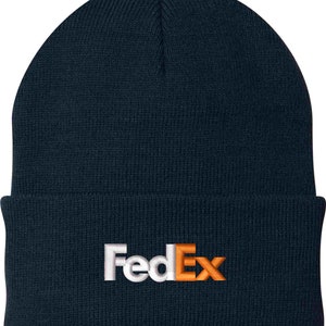 Pode incluir: Um gorro de malha azul marinho com um logotipo FedEx bordado em branco e laranja.