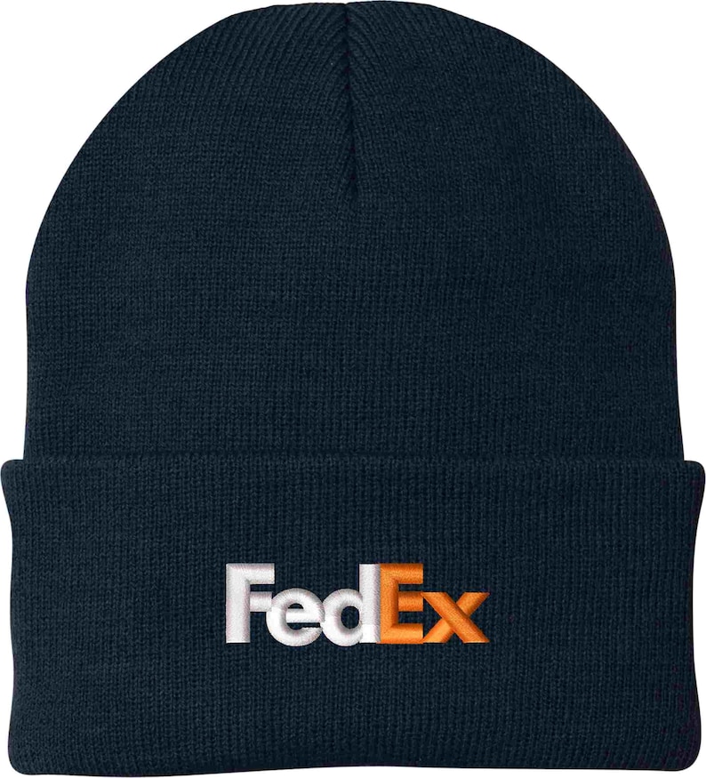 Pode incluir: Um gorro de malha azul marinho com um logotipo FedEx bordado em branco e laranja.