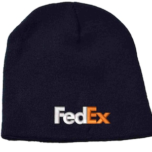 Pode incluir: Um gorro de malha azul marinho com um logotipo FedEx bordado em branco e laranja.